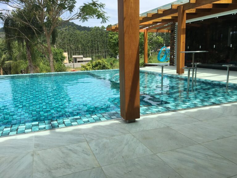 Piscina com pergolado de madeira e área gourmet integrada, projeto da Ramiro Piscinas no Alto Vale do Itajaí