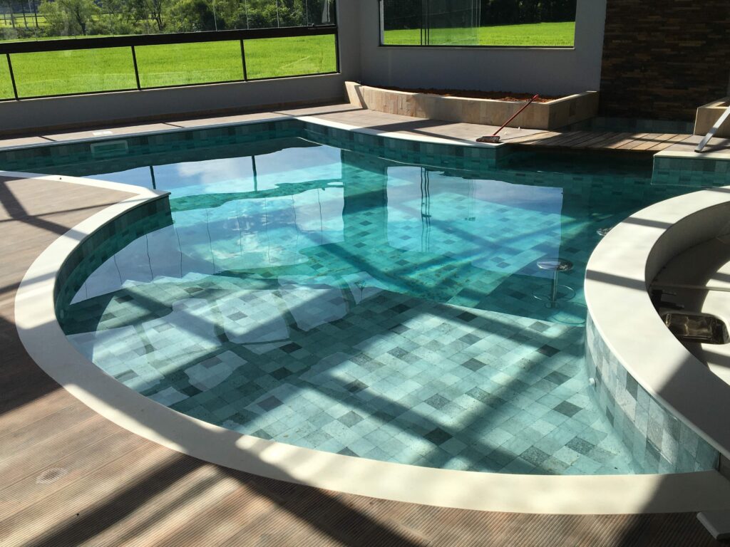 Piscina de formato livre com prainha e spa integrado revestida em pastilha