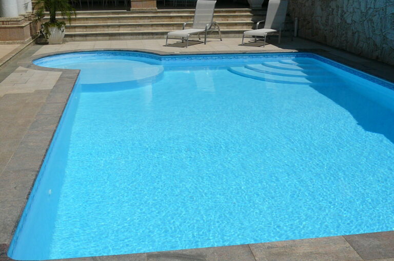 Piscina revestida em manta vinílica com deck amplo e espreguiçadeiras, projeto da Ramiro Piscinas