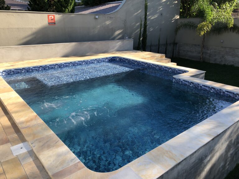 Piscina de alvenaria com prainha e hidromassagem, revestida em pastilha, projeto da Ramiro Piscinas