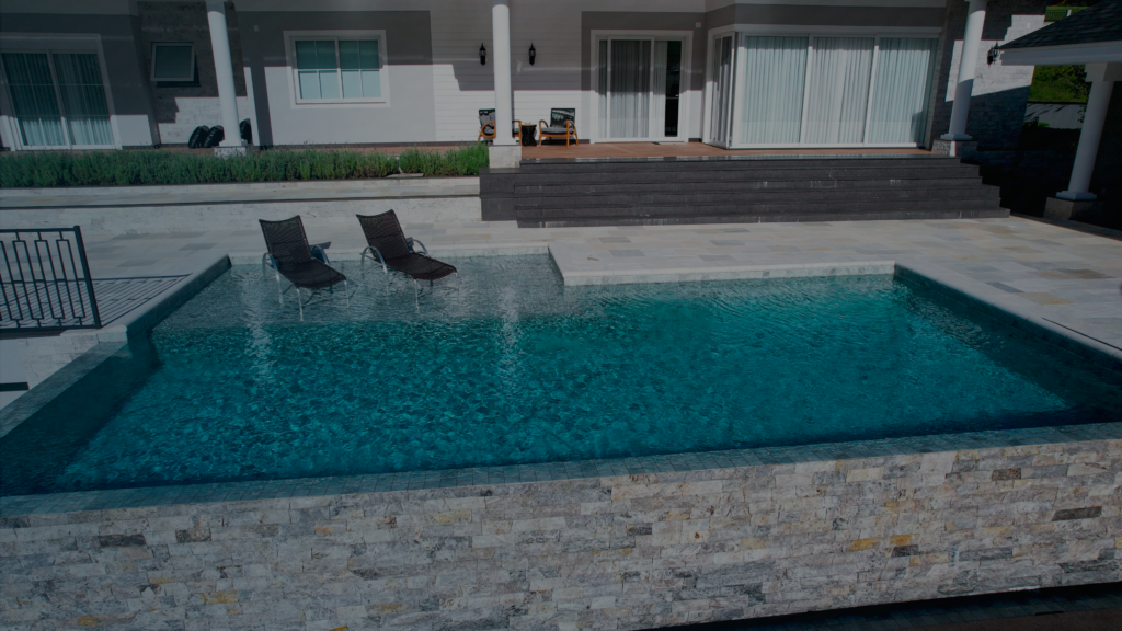 Piscina de alvenaria com borda infinita e deck em pedra natural em residência no Alto Vale do Itajaí